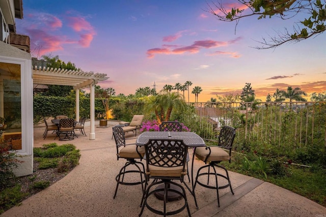 patio terrace at dusk with a pergola and outdoor dining area