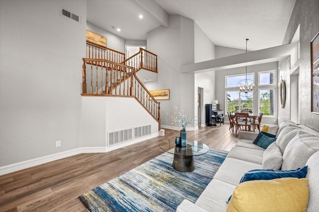 living room with a chandelier, stairs, baseboards, wood finished floors, and high vaulted ceiling