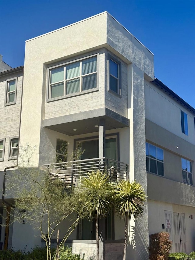 view of front of home featuring stucco siding and a balcony