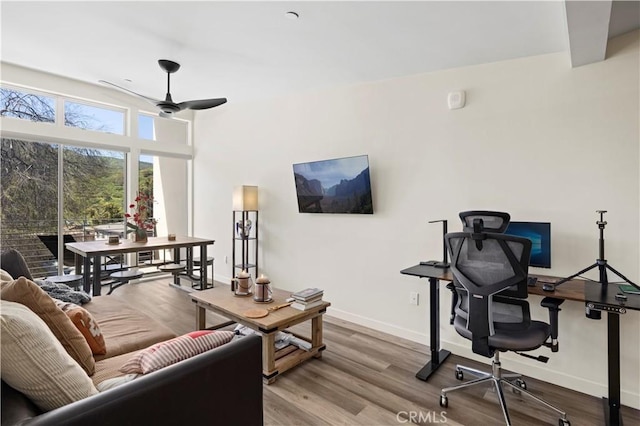 living area featuring wood finished floors, baseboards, and a ceiling fan