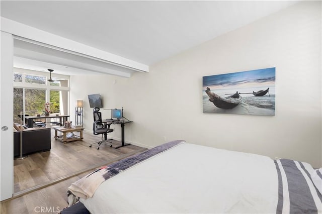 bedroom featuring wood finished floors, beam ceiling, an office area, and baseboards