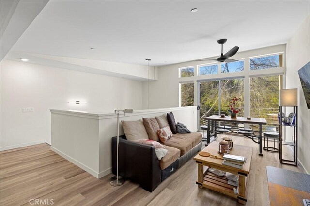 living area featuring wood finished floors, a ceiling fan, and baseboards