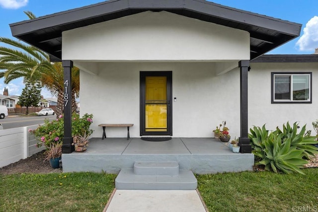entrance to property with a porch and stucco siding