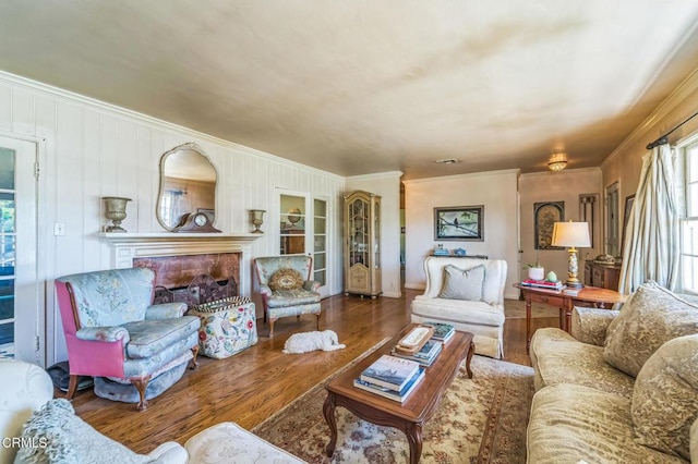 living room with crown molding, wood finished floors, and a fireplace