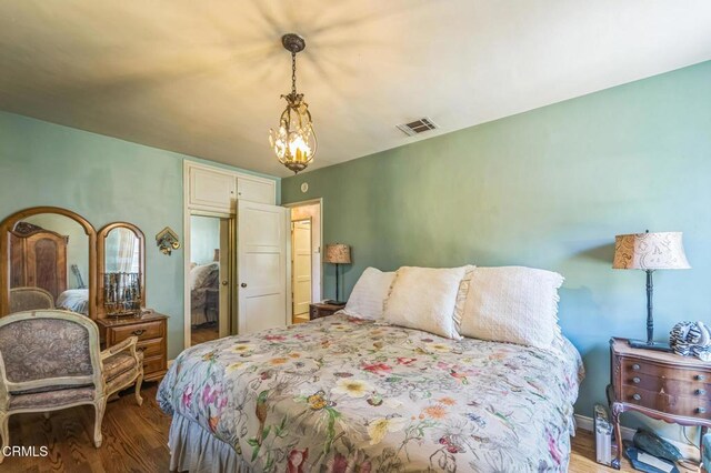 bedroom with wood finished floors and a chandelier