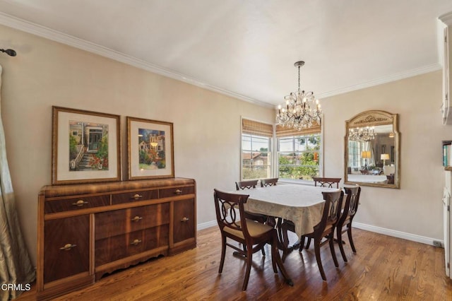 dining area featuring a chandelier, baseboards, wood finished floors, and crown molding