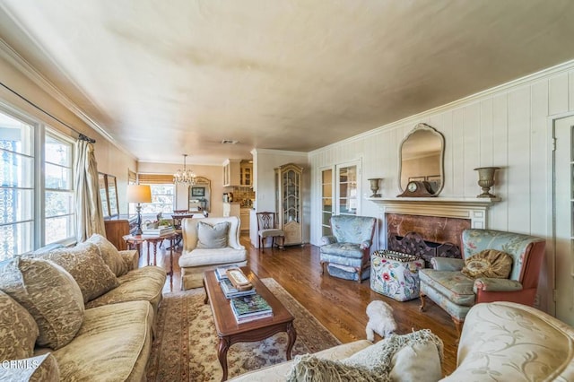 living room featuring wood finished floors, ornamental molding, a chandelier, and a fireplace