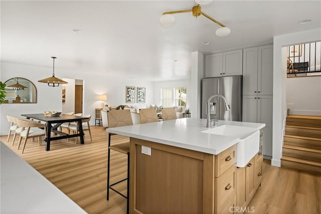 2153 Stanbridge Ave, Long Beach, CA 90815 - kitchen with stainless steel fridge with ice dispenser, a sink, light wood-type flooring, light countertops, and a center island with sink