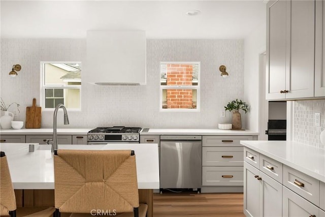 2153 Stanbridge Ave, Long Beach, CA 90815 - kitchen featuring stainless steel dishwasher, light countertops, wood finished floors, tasteful backsplash, and wallpapered walls