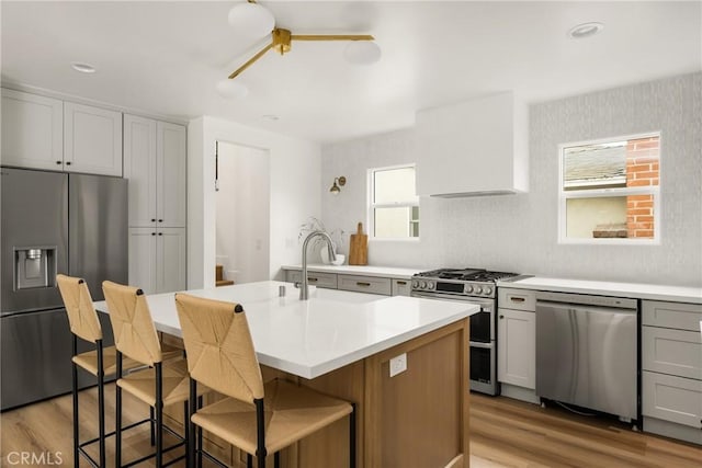 2153 Stanbridge Ave, Long Beach, CA 90815 - kitchen with stainless steel appliances, light wood finished floors, light countertops, a sink, and a kitchen island with sink