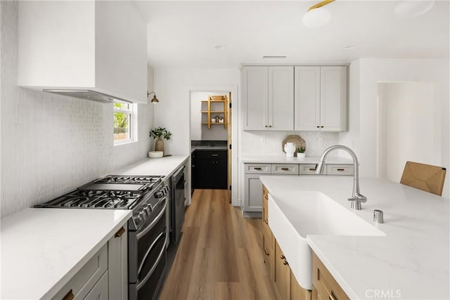 2153 Stanbridge Ave, Long Beach, CA 90815 - kitchen featuring double oven range, wall chimney exhaust hood, a sink, light wood-style floors, and tasteful backsplash