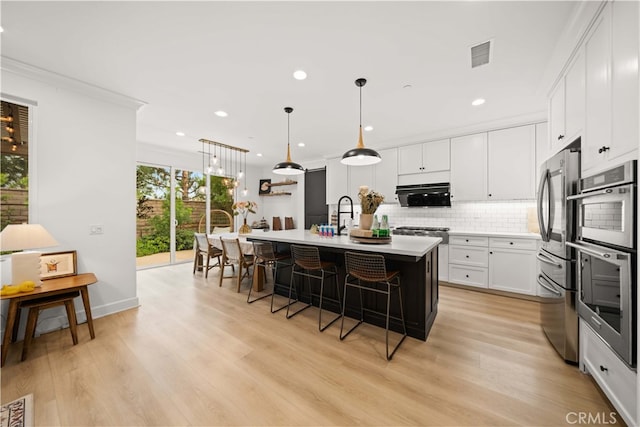 54 Painted Cameo, Irvine, CA 92602 - kitchen featuring stainless steel appliances, a breakfast bar, tasteful backsplash, a kitchen island with sink, and light countertops