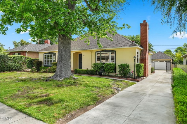 view of front facade with stucco siding, an outdoor structure, a front lawn, and driveway