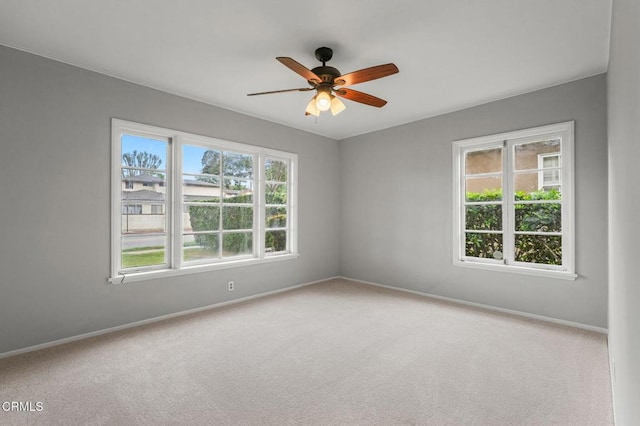 carpeted spare room with healthy amount of natural light, baseboards, and a ceiling fan