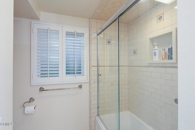 bathroom with bath / shower combo with glass door