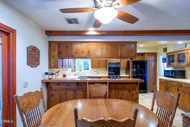 kitchen featuring black appliances, brown cabinets, a peninsula, a textured ceiling, and tasteful backsplash