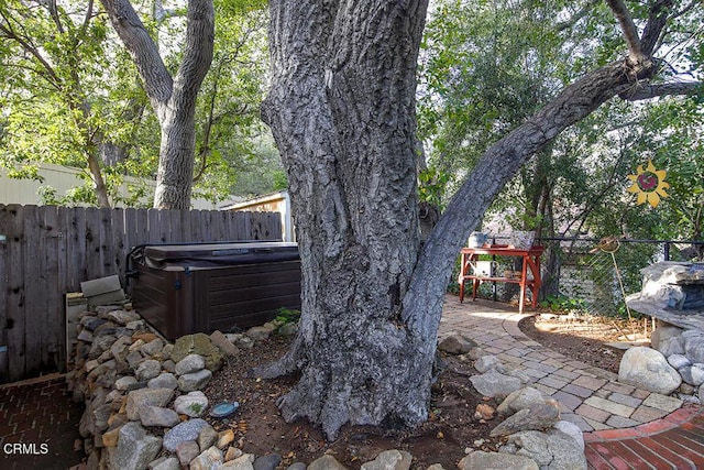 fenced backyard featuring a hot tub and a patio area