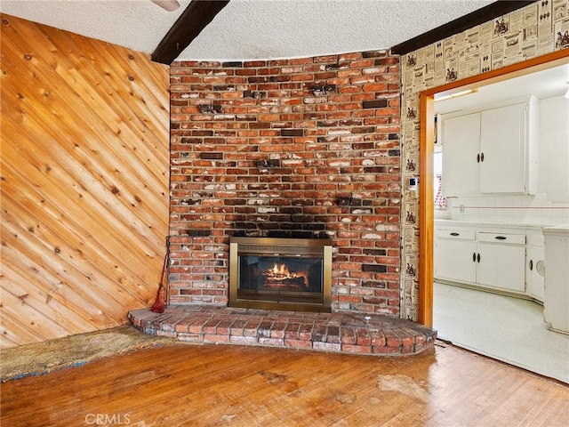 1234 N Ontario St, Burbank, CA 91505 - unfurnished living room with wood finished floors, a textured ceiling, a brick fireplace, beamed ceiling, and wood walls
