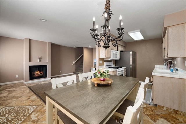 dining space featuring stairs, light stone finish flooring, a warm lit fireplace, baseboards, and recessed lighting