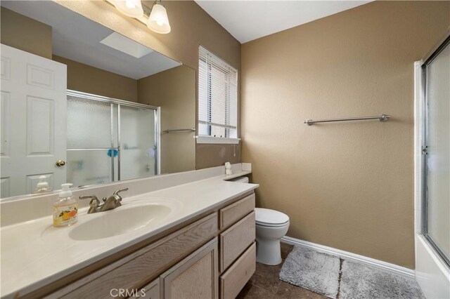 bathroom featuring a shower with door, vanity, toilet, and baseboards