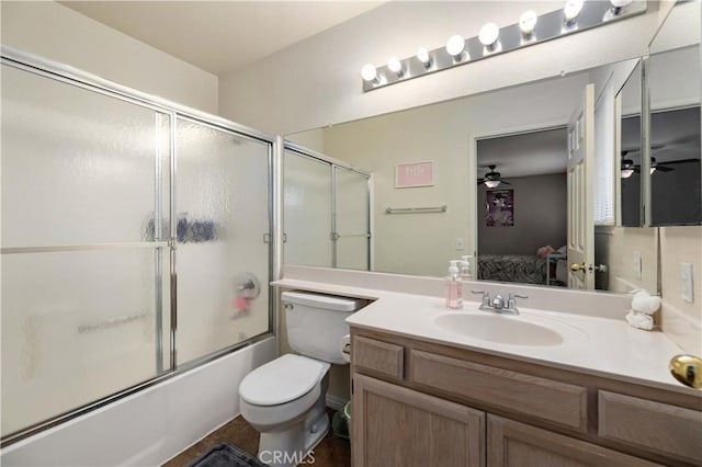 ensuite bathroom featuring ceiling fan, shower / bath combination with glass door, vanity, and toilet