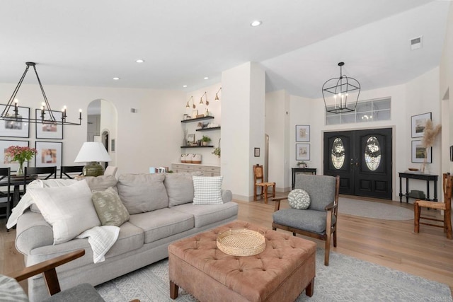 living area with a chandelier, arched walkways, light wood-style flooring, and recessed lighting