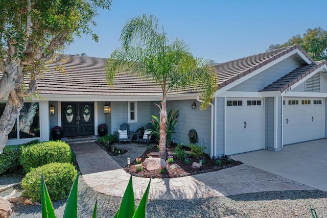 ranch-style house featuring a tiled roof, a garage, driveway, and a porch