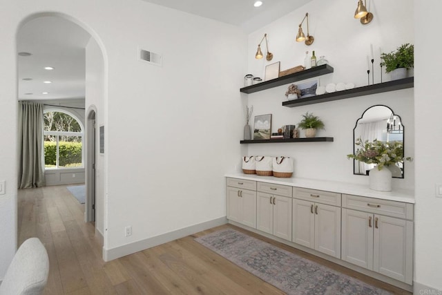 bar with recessed lighting, light wood-style flooring, arched walkways, and baseboards
