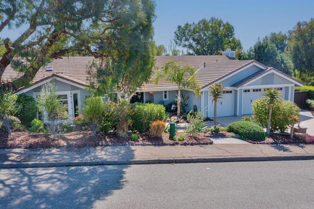 single story home with a tiled roof, a garage, driveway, and stucco siding