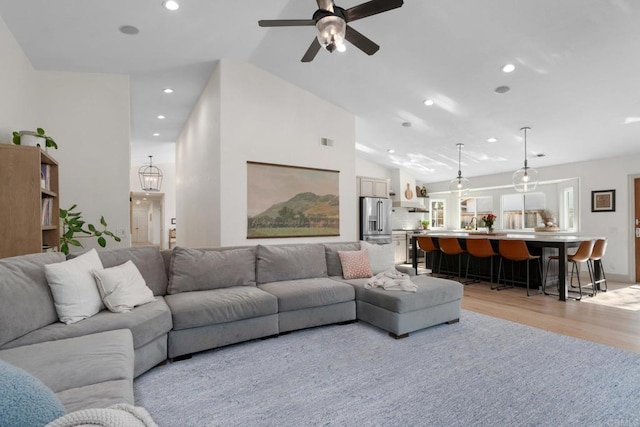 living area with light wood-style floors, recessed lighting, a ceiling fan, and vaulted ceiling