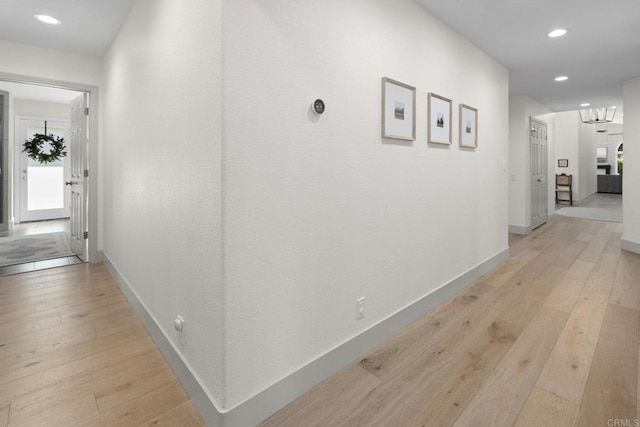 corridor with light wood-style flooring, baseboards, and recessed lighting