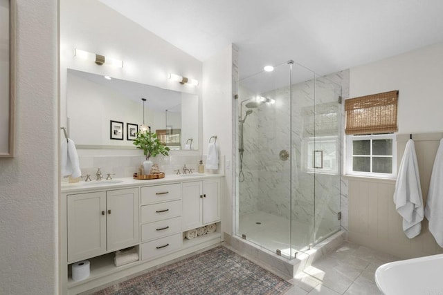 full bathroom with a marble finish shower, double vanity, and tile patterned floors