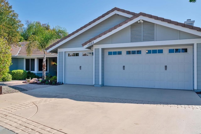 view of front of home with driveway, a tile roof, and a garage