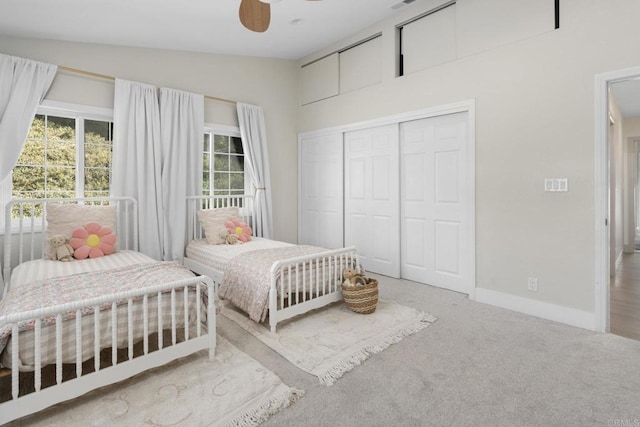 bedroom featuring lofted ceiling, multiple windows, baseboards, carpet flooring, and a closet