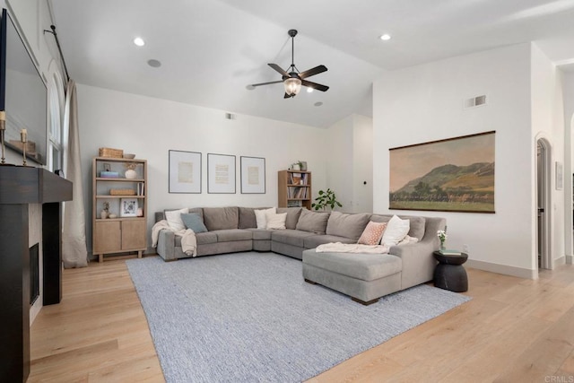 living room featuring light wood finished floors, a ceiling fan, baseboards, high vaulted ceiling, and recessed lighting