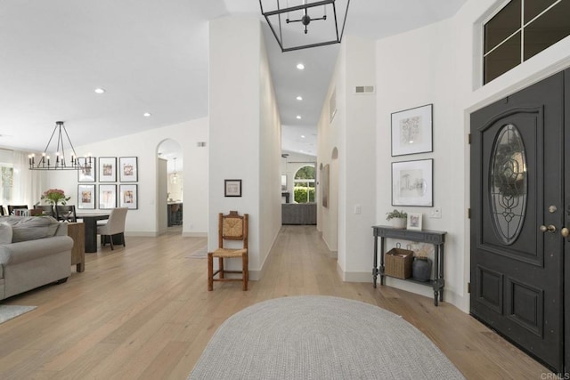 foyer with a chandelier, light wood-type flooring, arched walkways, recessed lighting, and baseboards