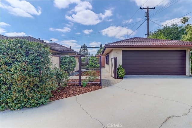 view of property exterior with fence, a garage, a tile roof, and stucco siding