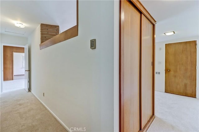 hall with light colored carpet and baseboards