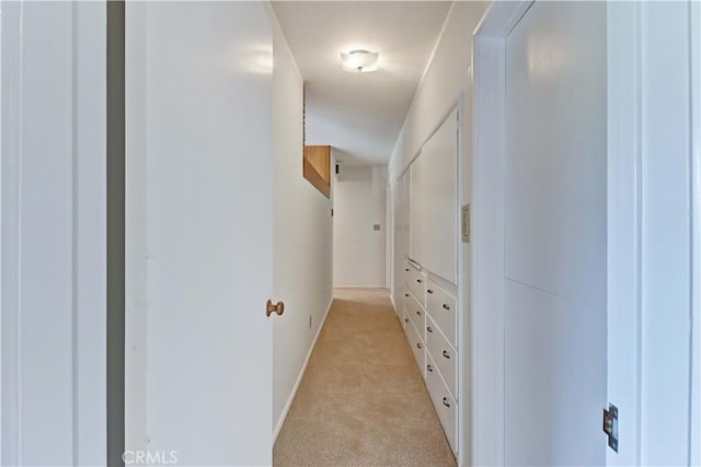 hallway featuring light carpet and baseboards