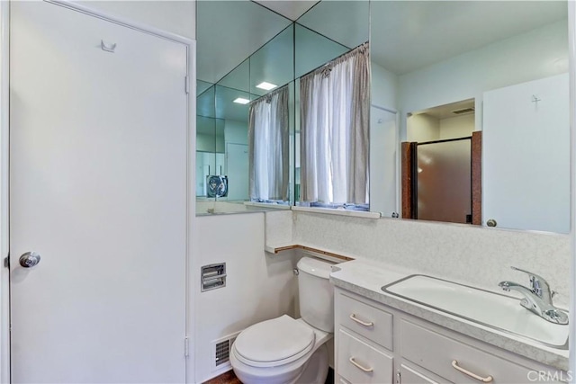 bathroom featuring toilet, vanity, and an enclosed shower