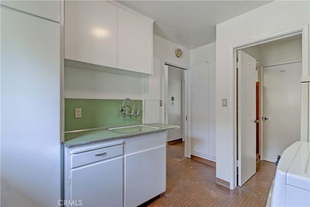 kitchen featuring a sink, white cabinetry, light countertops, washer / clothes dryer, and tile patterned floors