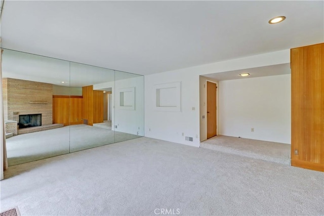 unfurnished living room featuring light colored carpet, a fireplace, and recessed lighting