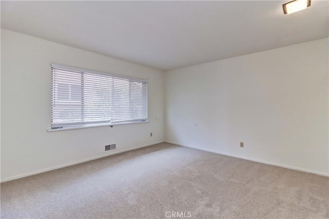 spare room featuring carpet floors and baseboards
