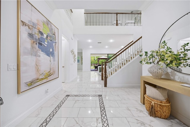 entrance foyer with light marble finish flooring, baseboards, stairs, and a high ceiling