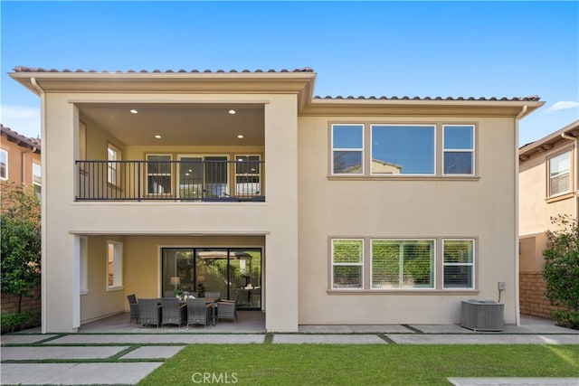 rear view of property featuring a balcony, stucco siding, a patio, and central air condition unit