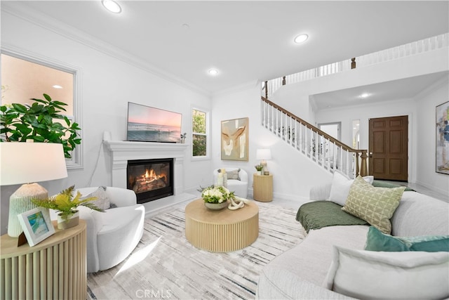 living area with ornamental molding, a glass covered fireplace, stairs, recessed lighting, and baseboards