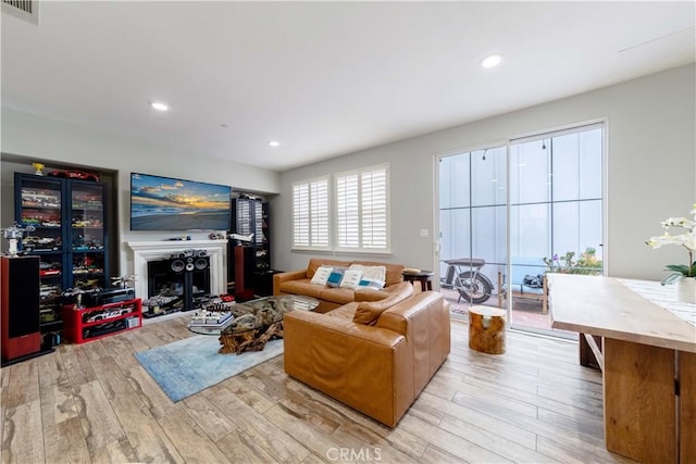 living area featuring light wood-style flooring, a fireplace, and recessed lighting