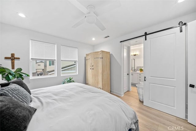 bedroom featuring a barn door, light wood-type flooring, recessed lighting, a ceiling fan, and ensuite bathroom