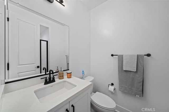 bathroom with toilet, vanity, and baseboards