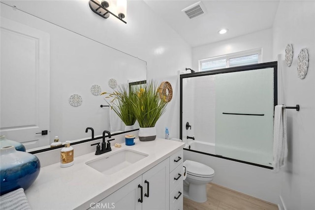 full bath featuring wood finished floors, vanity, toilet, shower / bath combination with glass door, and recessed lighting